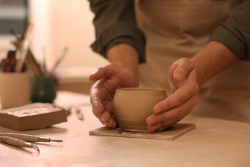 Fototapeta na wymiar Clay crafting. Man making bowl at table, closeup