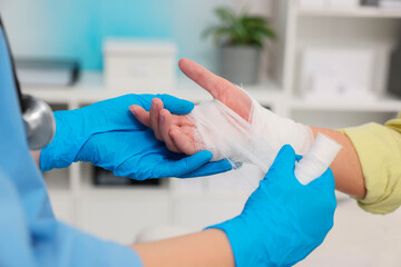 Obraz premium Doctor bandaging patient's burned hand in hospital, closeup