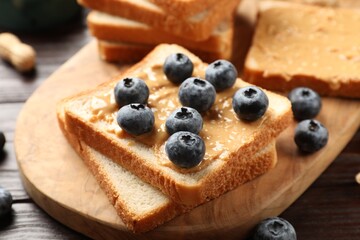 Delicious toasts with peanut butter and blueberries on table, closeup