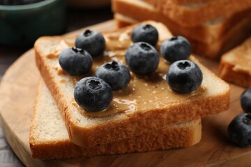 Delicious toasts with peanut butter and blueberries on table, closeup