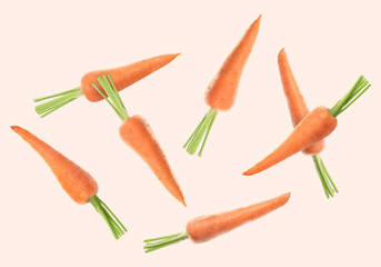 Fresh ripe carrots falling on beige background