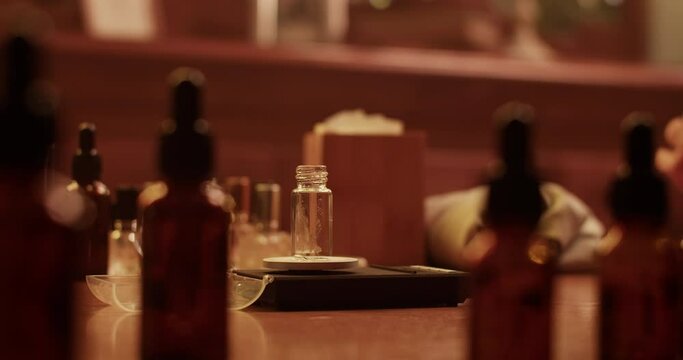 Crop male perfumer weighing bottle with oils on scales