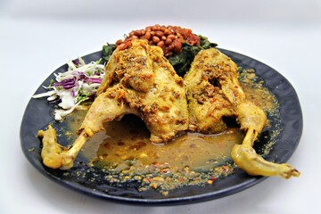 Balinese Indonesian food, Ayam Betutu. Whole chicken filled with Balinese seasoning cassava leaves, wrapped in banana leaves and steamed. Served with Sambal Matah and Roasted Peanuts.