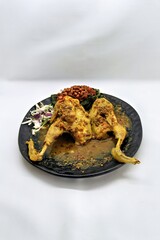 Balinese Indonesian food, Ayam Betutu. Whole chicken filled with Balinese seasoning cassava leaves, wrapped in banana leaves and steamed. Served with Sambal Matah and Roasted Peanuts.