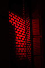 Red light shining through grated window.