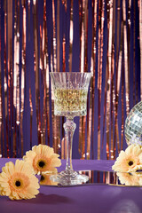 A glass of champagne on a Silver foil tinsel strips background with highlights for christmas and...