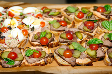 Assorted Gourmet Open Sandwiches for Catering. A variety of open sandwiches with meats, vegetables, and garnishes, ready to be served at a catered event or party.