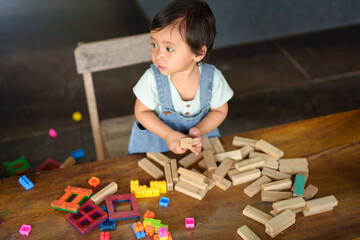 toddler girl playing wooden block toy on table