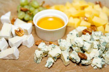 Gourmet Cheese Board with Honey and Nuts. An assortment of fine cheeses, including Brie and blue cheese, paired with honey and pecan nuts, arranged on a serving board.