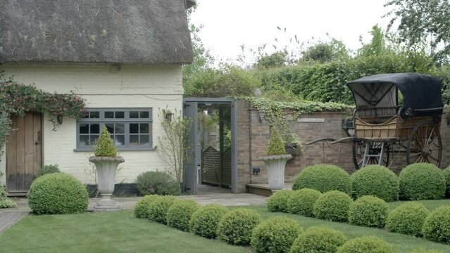 Right pan shot of an old english cottage with a carriage.