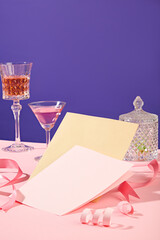 Two glasses of wine displayed over purple background with a luxury jar and a stack of paper. Text can be added to the copy space. Design creative concept