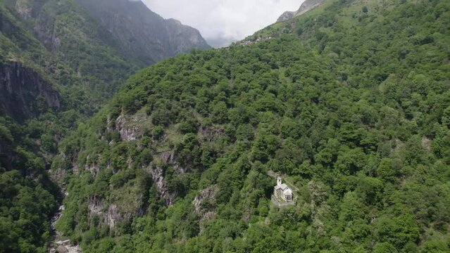  Mountain gorge below green forest mountain foothills church Italy AERIAL