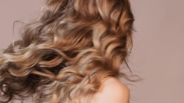 Woman turns his head, waving her long wavy ginger hair. Female hair beauty concept.