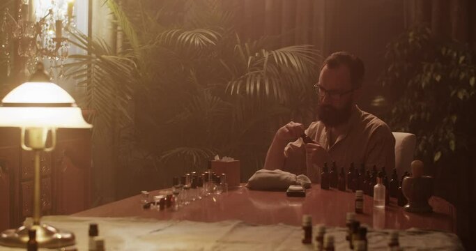 Male perfumer smelling oil while working on perfume