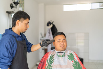 Client sitting on a barber shop while barber cutting hair