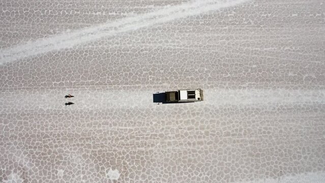 Bird's View Truck Driving Salar de Uyuni Bolivia, 2 eBikes Riding in Front. Cracked Salt Geometric Forms