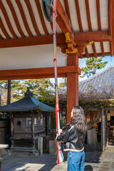 A young girl rings the bell to greet the deity in Japanese shrines.