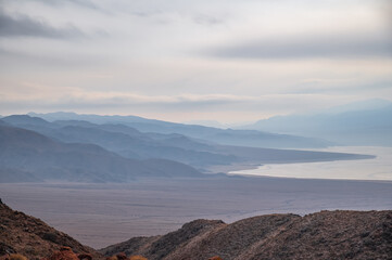 Bluish silhouettes of misty mountains and lake. Beautiful mountain landscape. Orto-Tokoy reservoir in Kyrgyzstan in winter.