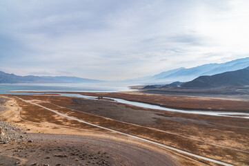 Bluish silhouettes of misty mountains and lake. Beautiful mountain landscape. Orto-Tokoy reservoir and the Chu river in Kyrgyzstan in winter.