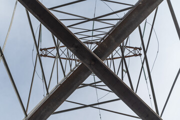 High-voltage power line support close-up. Metal pattern. View from below. The beauty of metal structures.