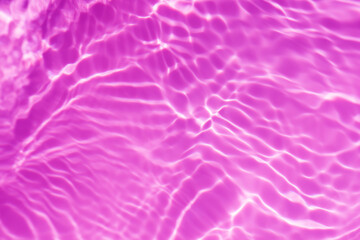 Purple water background. Pink water splashe on the surface ripple blur. Defocus blurred transparent pink colored clear calm water surface texture with splash and bubble. Water waves with shining.