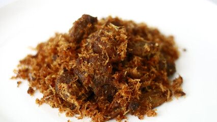 Beef serundeng on white background. Serundeng is an Indonesian food which is made from sauting grated coconut, and is often used as a side dish to accompany rice.