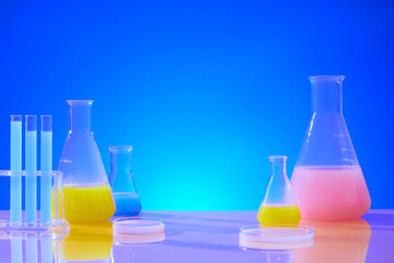 Test tubes, petri dishes and transparent Erlenmeyer flasks containing colored solutions are...