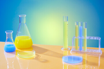 Yellow and blue solutions are contained in test tubes, Erlenmeyer flasks and petri dishes on a...