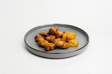 fried chicken nuggets in sauce in a flat plate on a white background side view
