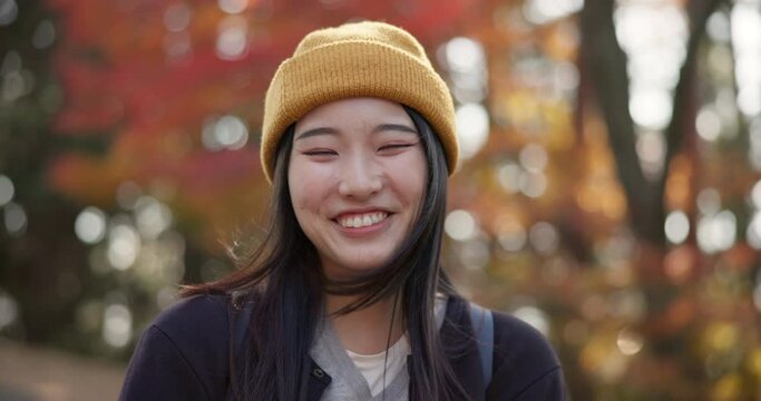 Happy, face and a Japanese woman in nature for holiday, freedom or relax. Smile, autumn and portrait of a beautiful, young and model in the woods, park or garden of Japan for an outdoor vacation