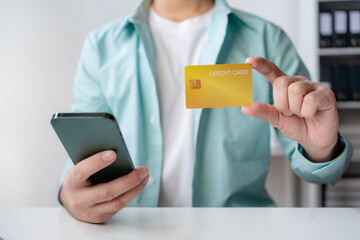 Man making financial transaction using credit card and smartphone. Young man paying online, using banking service, entering information, shopping, ordering in internet store, doing secure payment.