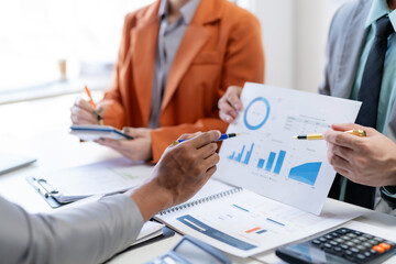 Meeting of business people pointing at graph. Group of businesspeople discussing together at a meeting.