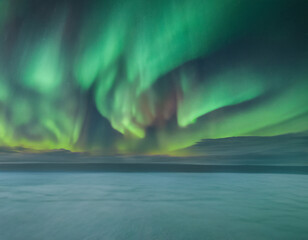 The Arctic night sky is illuminated by the mesmerizing Aurora Borealis, swirling in vibrant colors of green, blue, and purple, creating a celestial spectacle that mesmerizes the viewer.