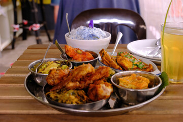 A bowl of Blue Butterfly Pea Flower coconut rice served with a few popular local dishes like...