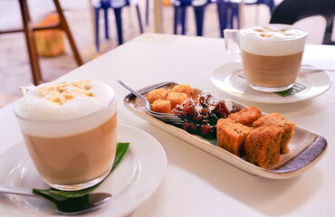 A plate of bite size cake snacks or kuihs, served with cappuccinos, in a restaurant. This selection...
