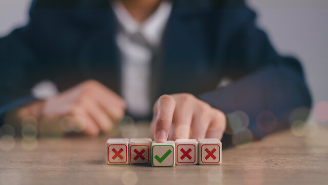 Hand-pushing the green correct sign symbol in front of the Red Cross sign on a wooden block cube for business proposal and document approve concept.