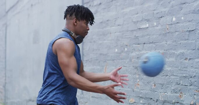 Black man, fitness and ball in exercise on wall for workout, muscle or outdoor training. Active African male person throwing round bouncing object for cardio, strength or endurance on concrete