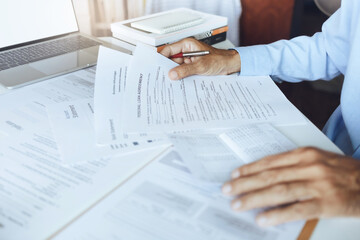 Hand of businessman holding personal loan agreement documents checking contract details and amount in the passbook to apply for a loan to start a new business