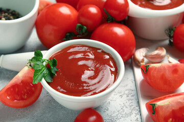 Bowl with tasty ketchup and fresh vegetables on light background, closeup