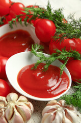 Bowl with tasty ketchup and fresh vegetables on table, closeup