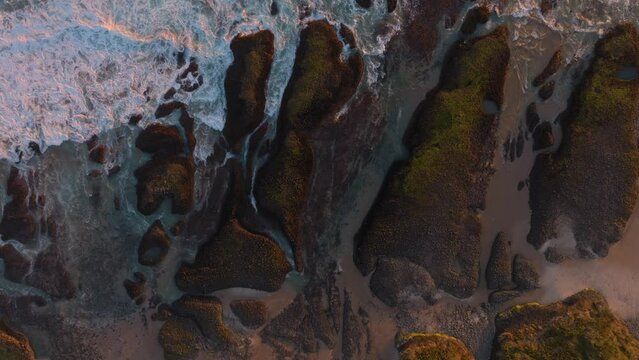 Aerial: Abstract texture of waves crashing over rocks. Hokianga Harbour, Opononi, Northland, New Zealand.