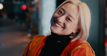 Woman, portrait and smile in city at night on Japanese street for explore, vacation or bokeh. Female person, face and happy in urban town for party adventure for tourism travel, fashion or confidence