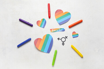 Text LOVE IS LOVE with paper hearts, transgender symbols and pens on white background