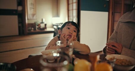 Asian child, family home and bored at dinner with parents for food, tired or night in dining room....