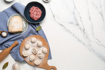 Fototapeta na wymiar Wooden board with uncooked dumplings and ingredients on white marble background