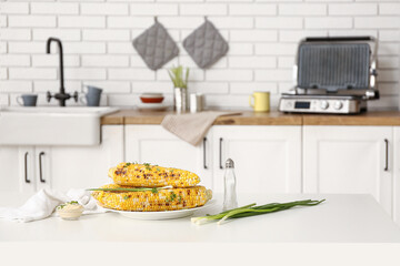 Plate with tasty grilled corn on table in kitchen