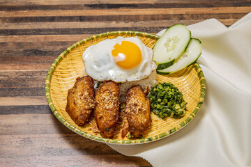 Chicken Wings with Fried Egg sunny side up and Rice served in dish isolated on wooden table top view of hong kong fast food