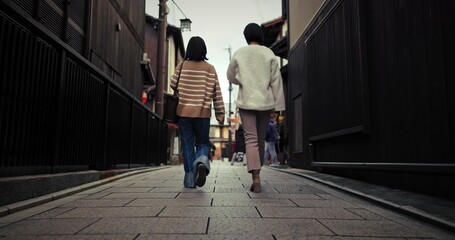 Women, walking and back by city street and travel for bonding in urban town in winter. Friends,...