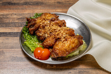 Gaarlic Butter Chicken Wings with lettuce leaf and tomato served in dish isolated on wooden table top view of hong kong fast food