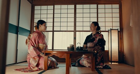 Women in traditional Japanese tea house, kimono and relax with conversation, respect and service. Friends at calm tearoom together with matcha drink, zen culture and ritual at table for ceremony.